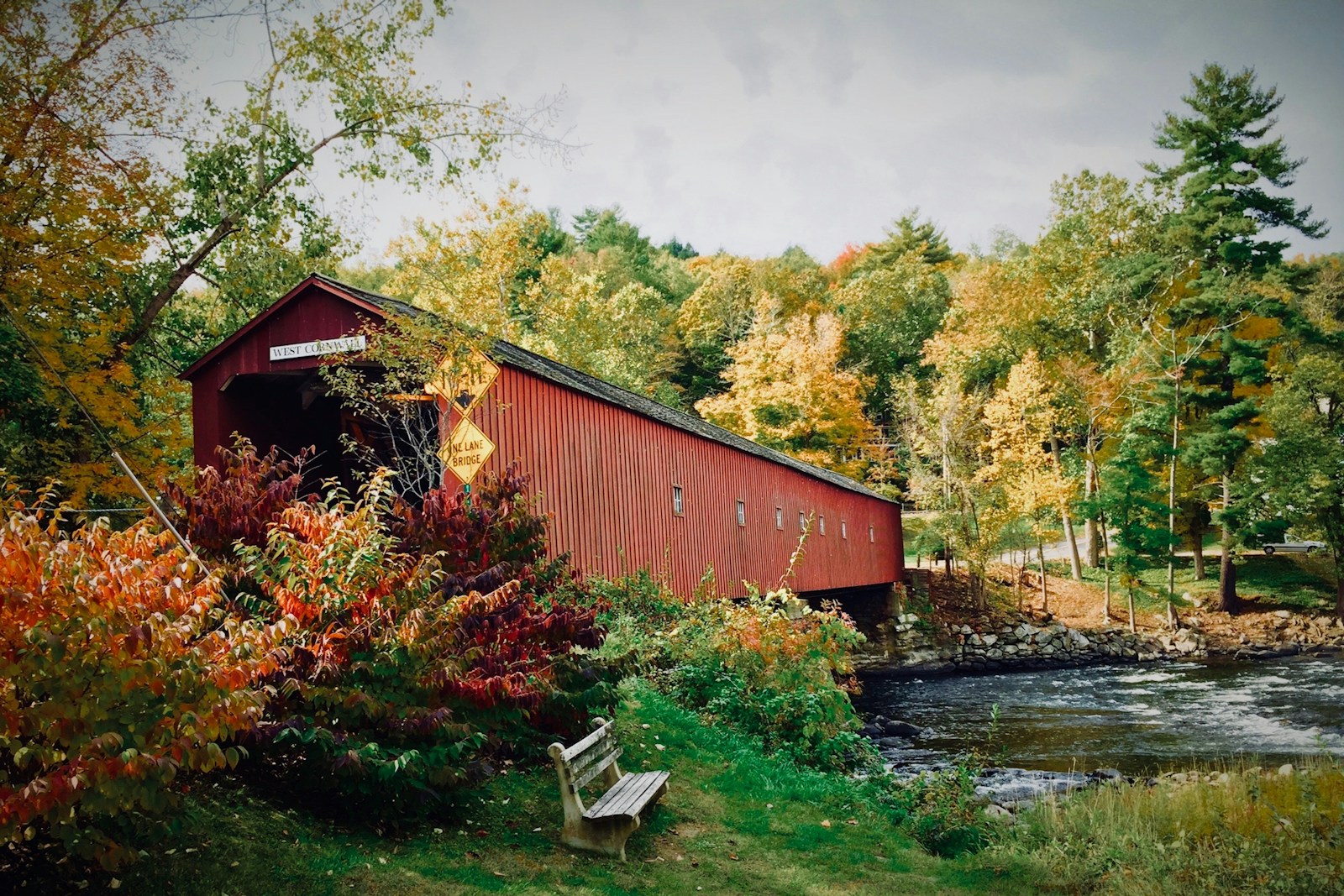 brown shack beside river covered bridge new england