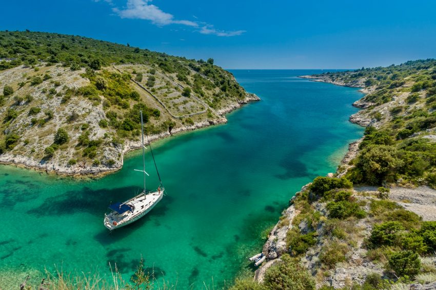 aerial photography of white boat near body of water between green mountain during daytime Greece island boat