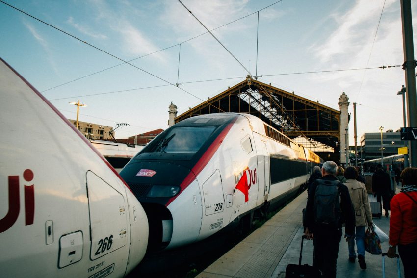 A group of people standing next to a train, France TGV
