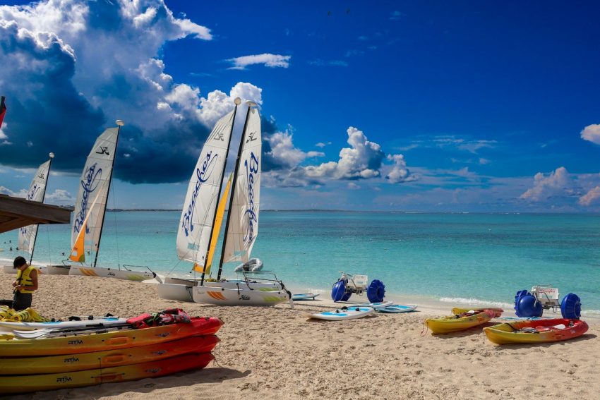 A group of sail boats sitting on top of a sandy beach