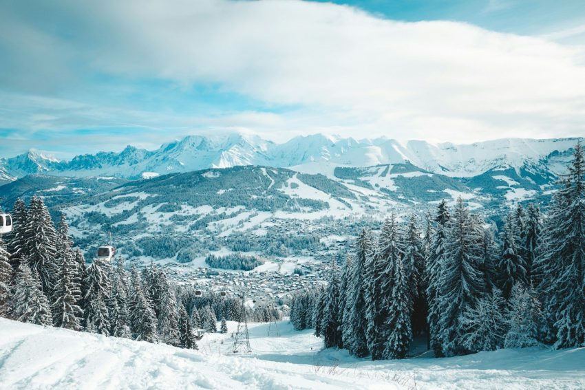 a snow covered mountain with trees and a ski lift in the distance
