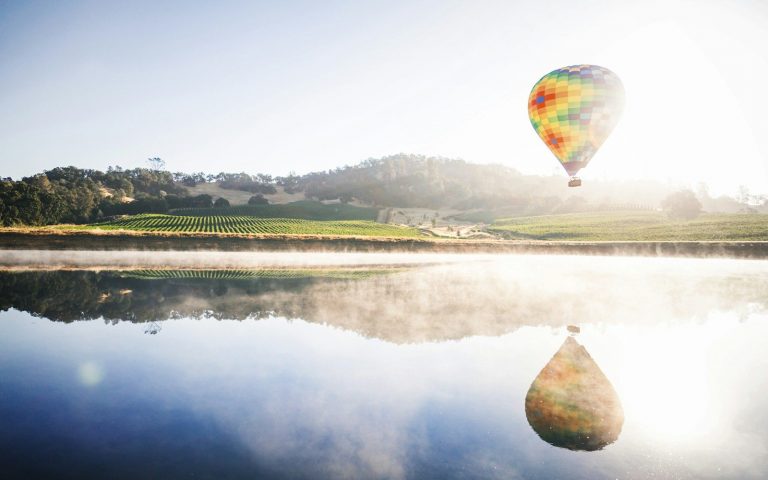 hot air balloon floating in mid air above body of water, Napa Valley California