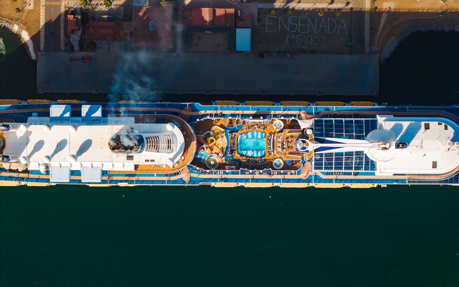 Stunning aerial shot of a cruise ship docked at Ensenada, Mexico, showcasing its pool deck.
