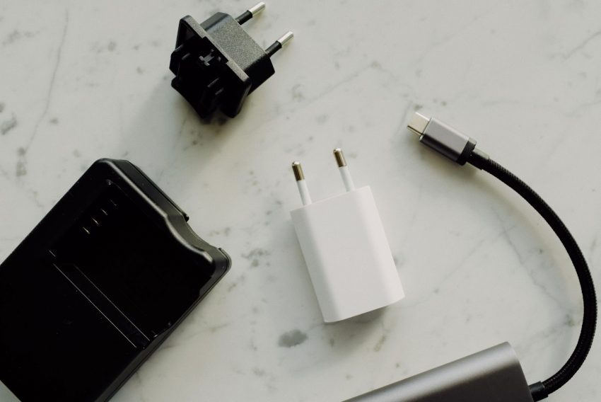 Flat lay of electronic adapters and chargers on a marble background.