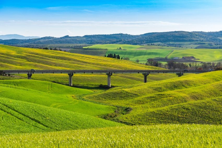 Panoramic view of vibrant green hills and bridge in Tuscany, Italy.