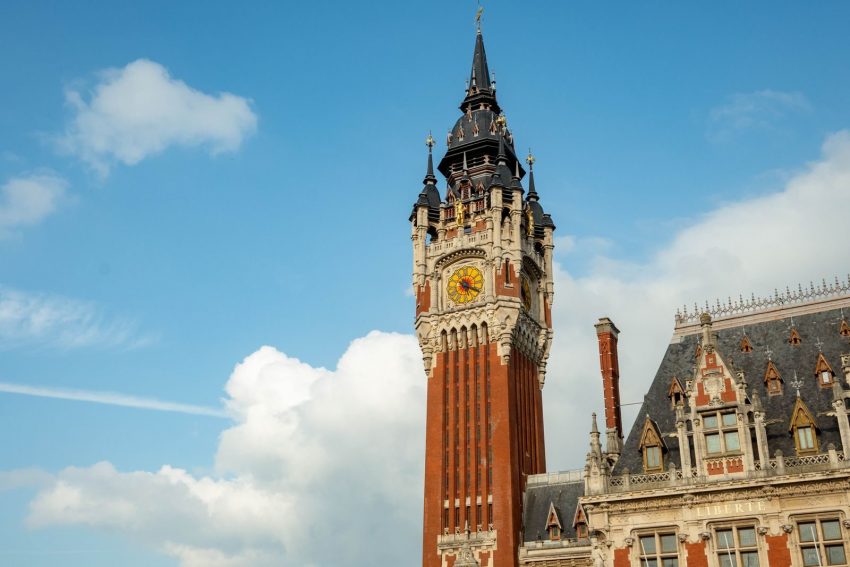 Stunning view of the iconic Belfry of Calais against a blue sky, showcasing neo-Gothic architecture.