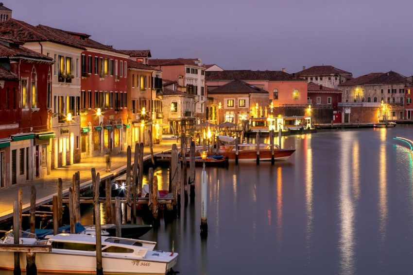 Serene view of Venetian canal at twilight with illuminated architecture and boats.