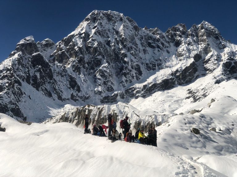 Group of climbers ascending snowy Himalayan peak under bright blue sky.